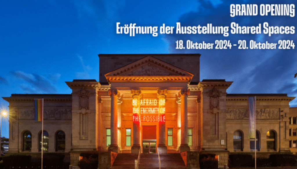 Erleuchtete Ruhmeshalle am Abend, Schriftzug "Grand Opening Eröffnung der Ausstellung Shared Spaces 18. Oktober 2024- 20. Oktober 2024