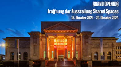 Erleuchtete Ruhmeshalle am Abend, Schriftzug "Grand Opening Eröffnung der Ausstellung Shared Spaces 18. Oktober 2024- 20. Oktober 2024