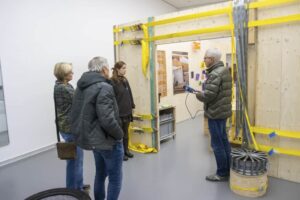 Vier Personen stehen vor einem gelben Holzgerüst in der Ausstellung "Shared Spaces" in der Kunsthalle Barmen