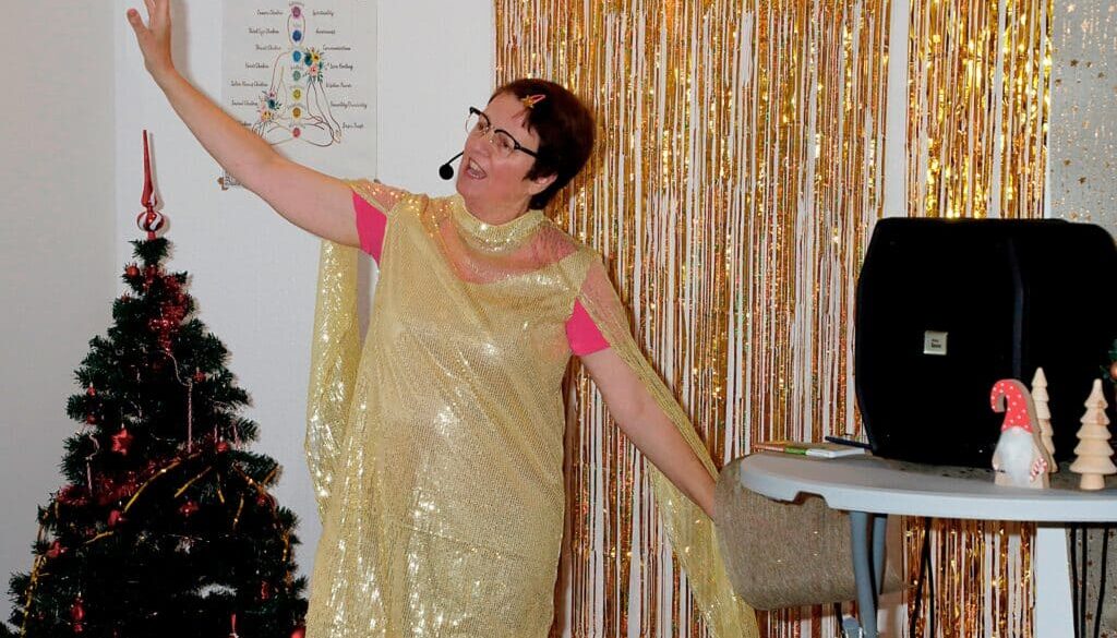 Dörte aus Heckinghausen singt im goldenen Kleid in schwungvoller Pose, im Hintergrund ein Weihnachtsbaum und -deko