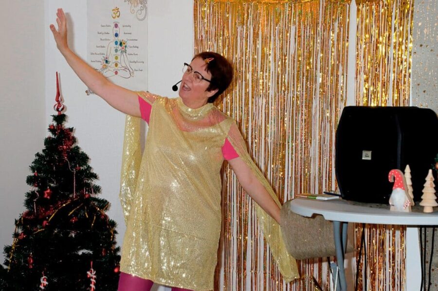 Dörte aus Heckinghausen singt im goldenen Kleid in schwungvoller Pose, im Hintergrund ein Weihnachtsbaum und -deko